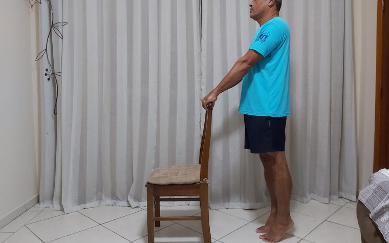 Trabalho de panturrilhas de pé com apoio de uma cadeira